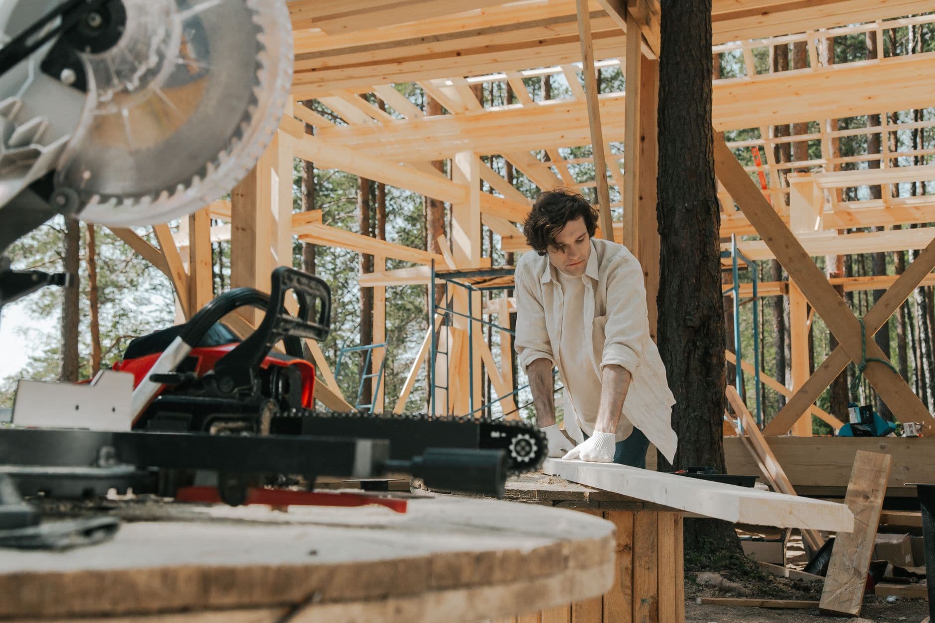 Carpenter cutting timber on a mitre saw at a framed jobsite