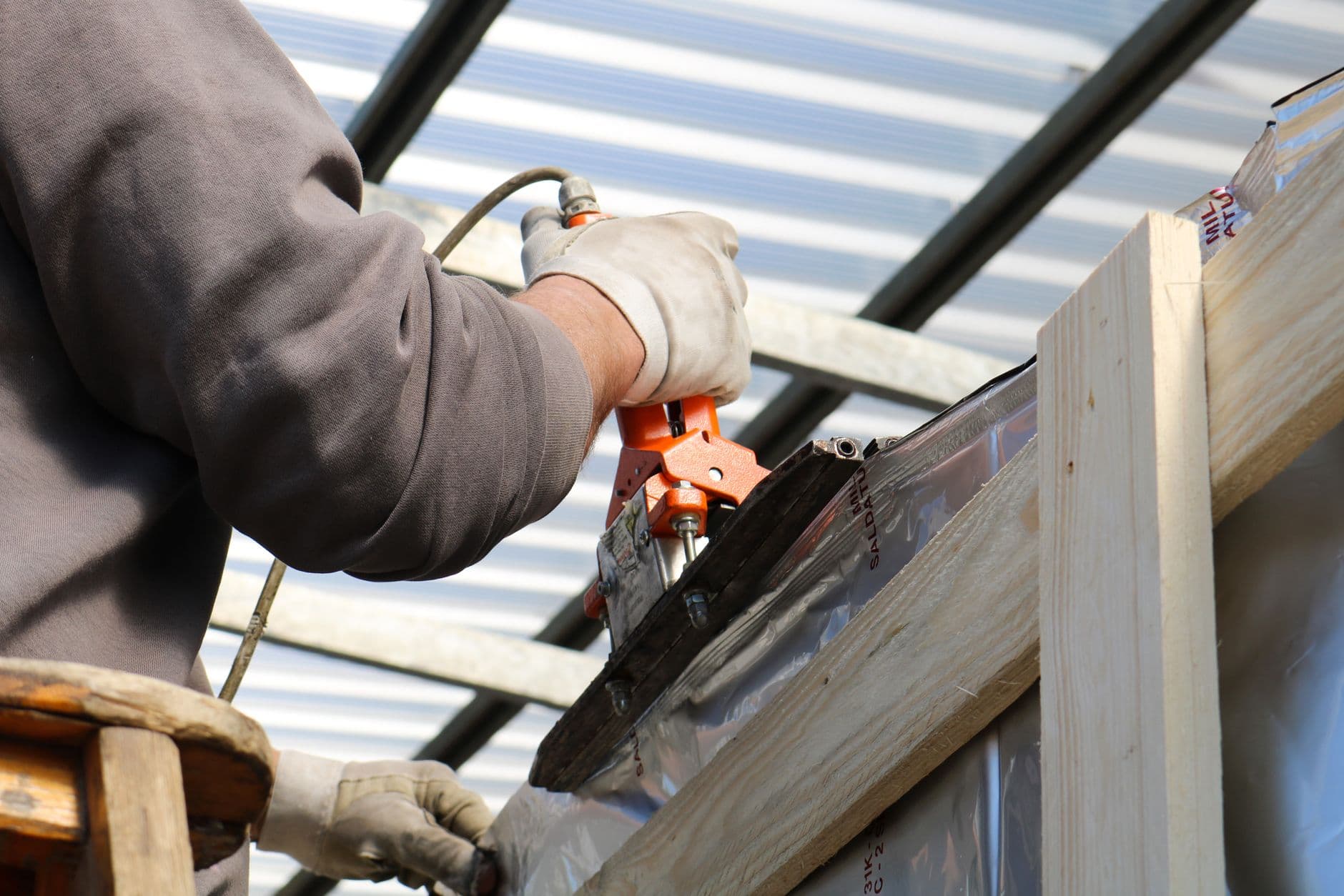 Gloved hands fixing timber framing with a power tool