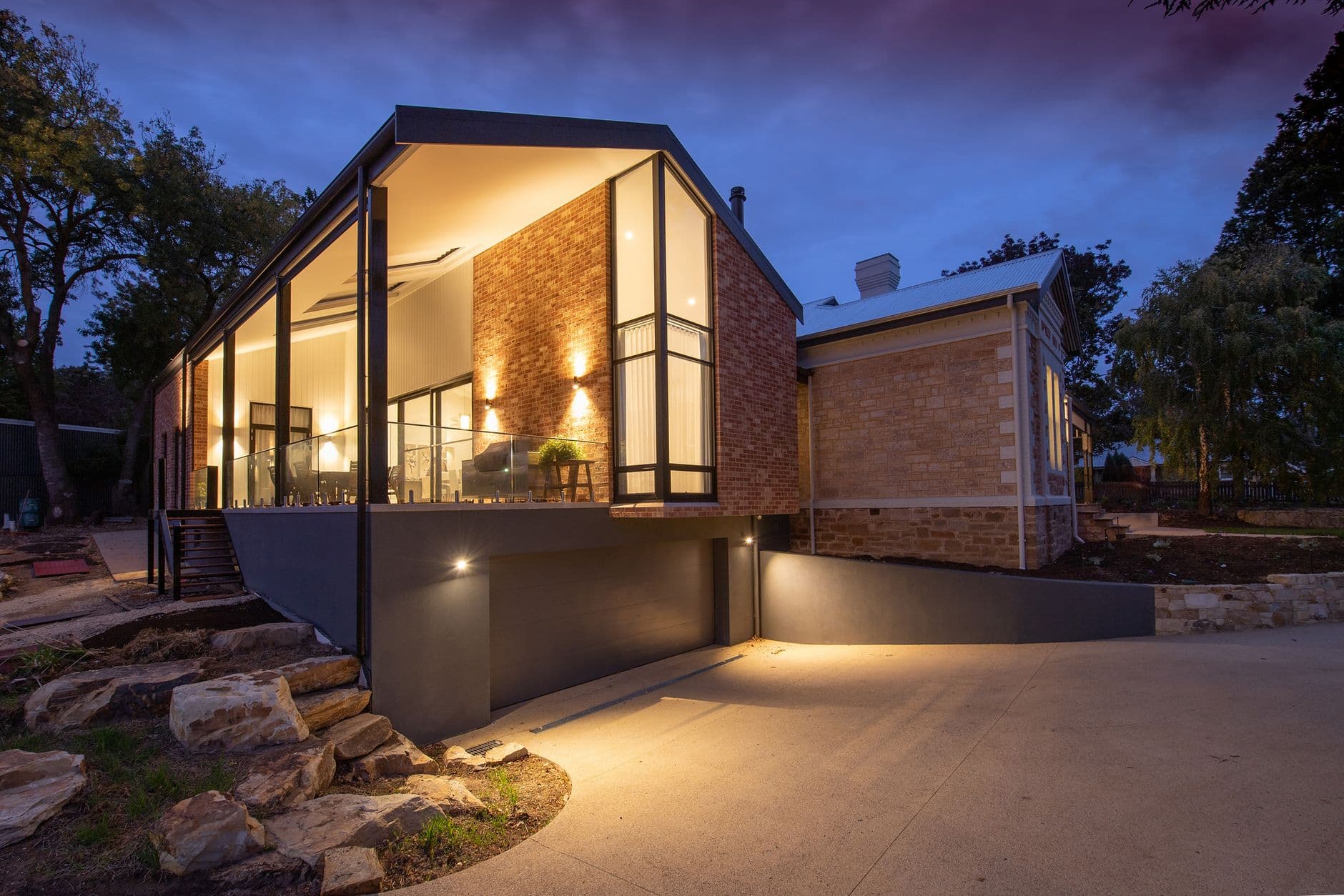 Contemporary gabled house with full-height glazing glowing at dusk