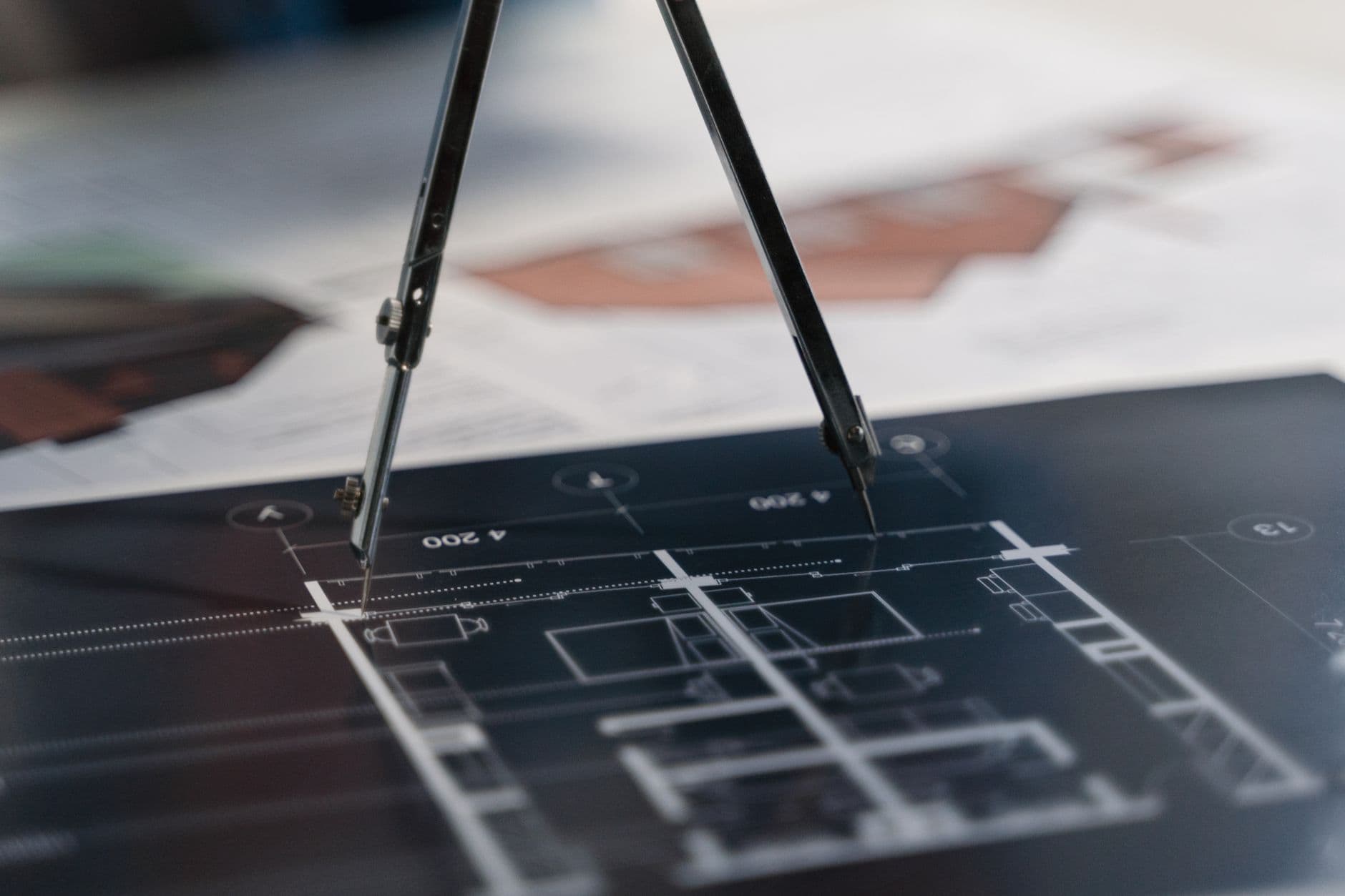 Compasses resting on a set of architectural blueprints