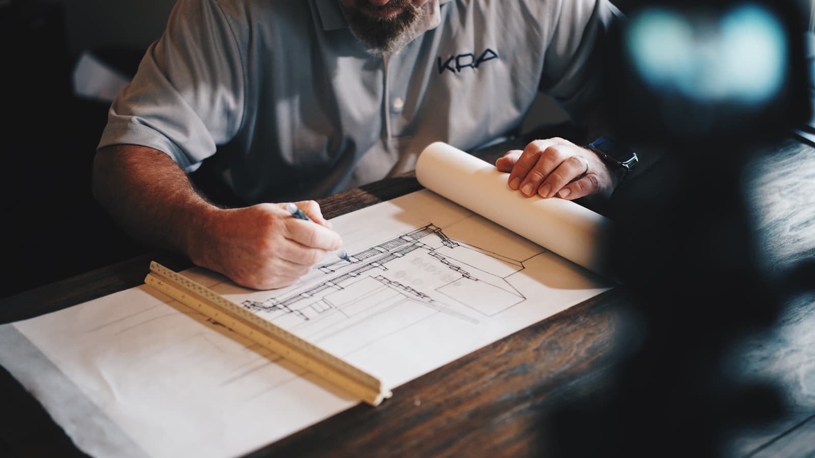 Builder reviewing rolled architectural drawings at a workbench