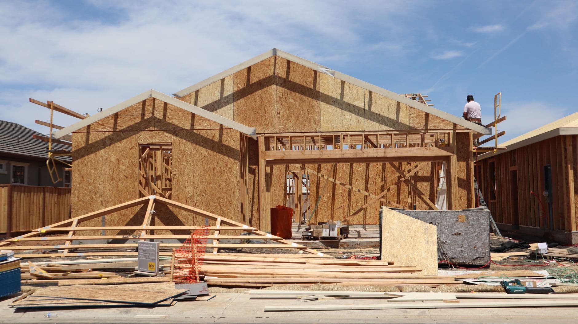 New home at the framing stage, timber roof trusses set against a clear sky