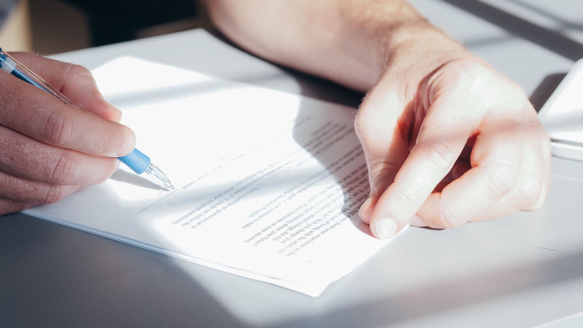 Hands signing a construction contract with a pen